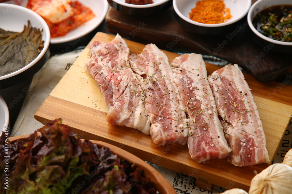 밑반찬과 생돼지고기가 있는 상차림 Table set with side dishes and raw pork