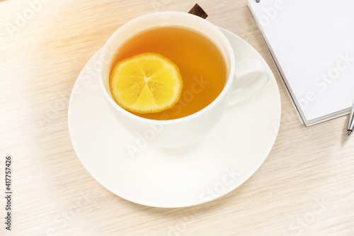 Close-up of a white cup with lemon tea on the background of a notebook.