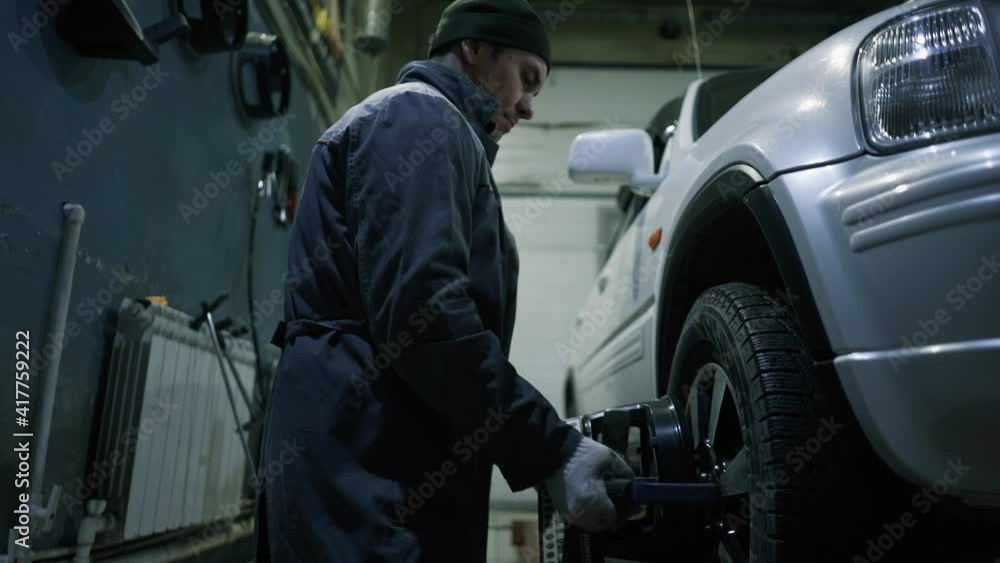 The car mechanic puts special sensors on the wheels to adjust the wheel camber. The car mechanic puts special sensors on the wheels to adjust the wheel camber.
