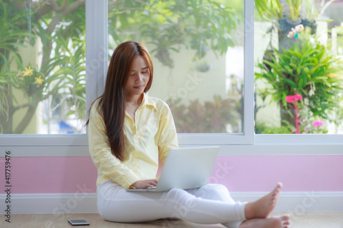 asian woman work at home with laptop sit down on floor with happiness and joyful