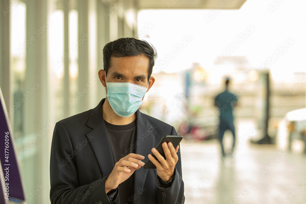 Young business men use mobile phones for work And wearing a mask to prevent the corona virus in public places