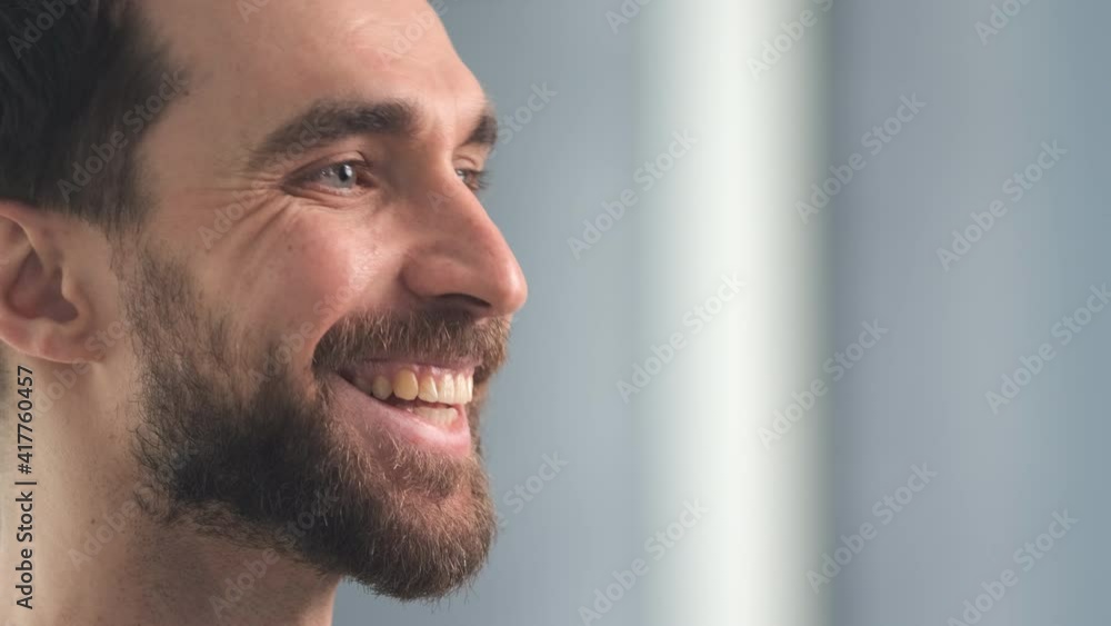 The smiling bearded man posing on camera indoor. slow motion The smiling bearded man posing on camera indoor. slow motion