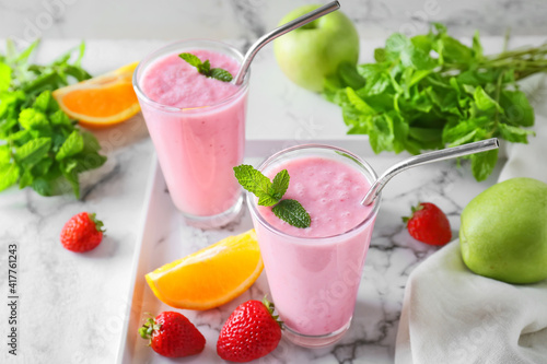 Glasses of tasty fruit smoothie on light background