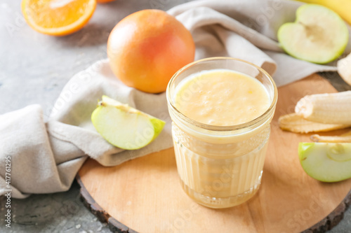 Glass of tasty fruit smoothie on grunge background