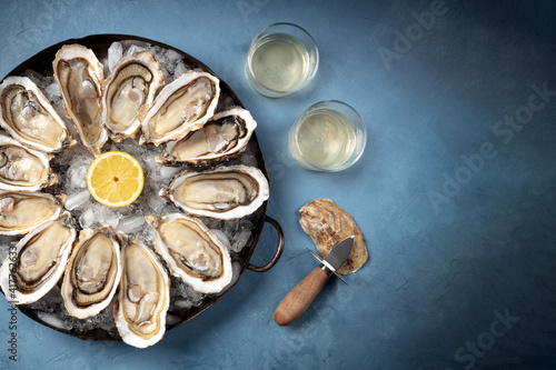Oysters with wine, an overhead flat lay shot with a place for text on a blue background