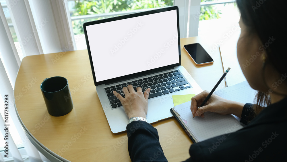 Businesswoman working on laptop computer and writing on agenda at office. Businesswoman working on laptop computer and writing on agenda at office.
