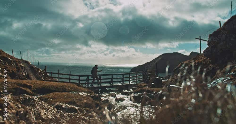 Man crossing a wooden bridge with ocean landscape Man crossing a wooden bridge with ocean landscape