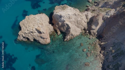 Top Down Aerial Zoom Out of Cliffs Cascading into the Blue Aegean Sea in Milos photo