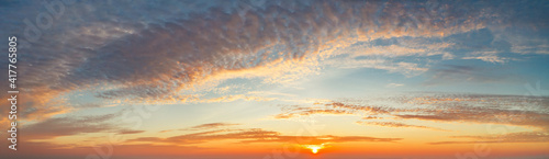 panoramic view from an airplane on a beautiful saturated sunrise above the clouds in red and orange shades
