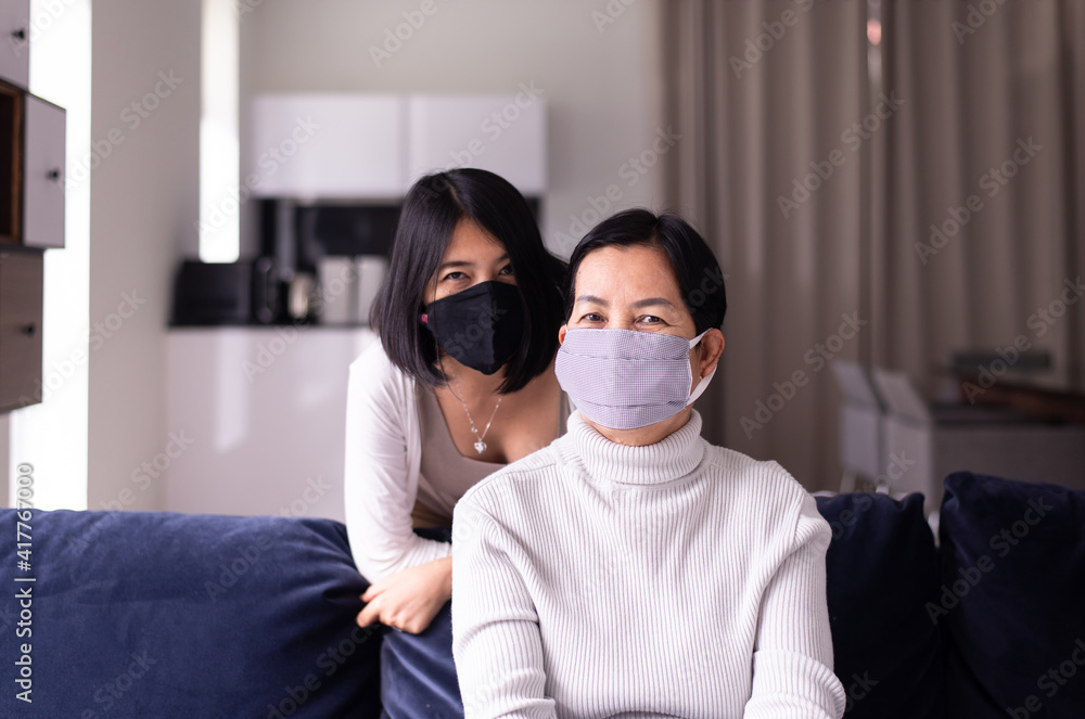 Senior asian woman and daughter wearing masks protect corona virus or covid-19 at home,SARS cov-2 infection Senior asian woman and daughter wearing masks protect corona virus or covid-19 at home,SARS cov-2 infection
