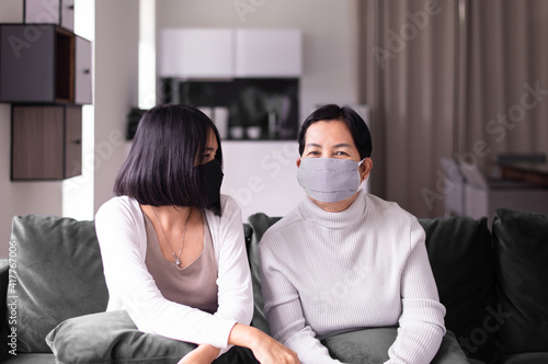 Senior asian woman and daughter wearing masks protect corona virus or covid-19 at home,SARS cov-2 infection