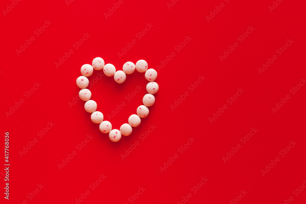 Heart shaped candy in shape of heart on red background. Valentine 8 March Mother Women's Day or sales concept. Creative romantic love pattern. Copy space, flat lay, top view