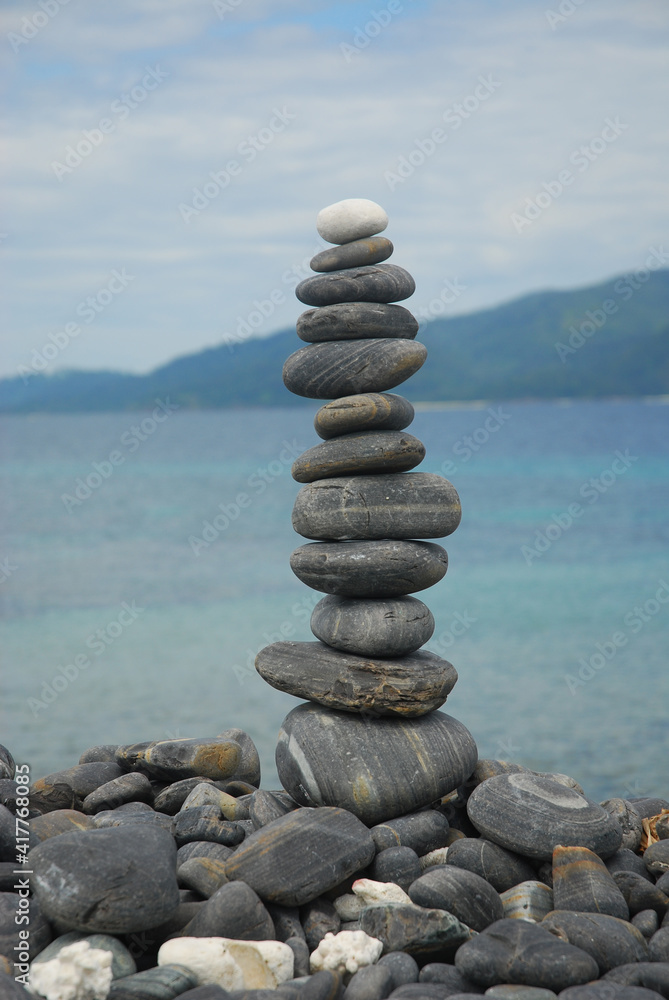 Fototapeta premium Pebbles are piled on a volcanic rock by the sea. Zen concept. Copy space.