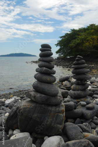 Pebbles are piled on a volcanic rock by the sea. Zen concept. Copy space.