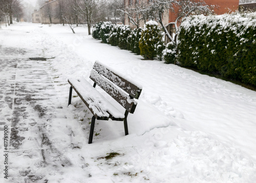Принти на полотні snowy bench on the side of the pedestrian road, snow covered the park area on a
