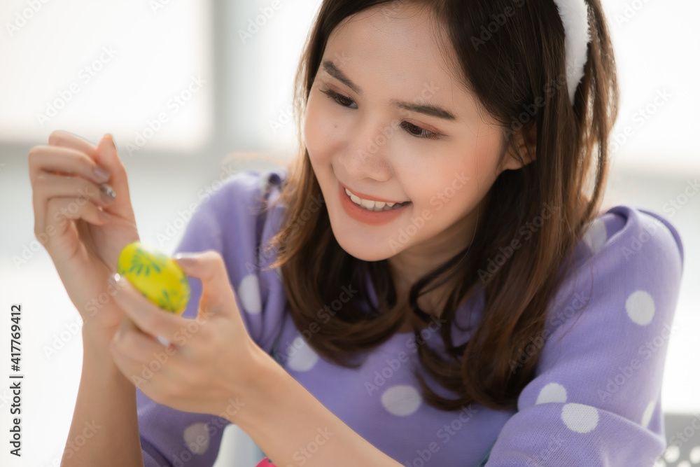 Easter Egg Festival. Asian women smiling faces. Put a bow tie on the head Hand painted various color easter eggs in white room, easter egg festival idea Easter Egg Festival. Asian women smiling faces. Put a bow tie on the head Hand painted various color easter eggs in white room, easter egg festival idea