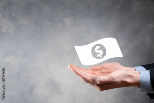 Businessman man holding money coin icon in his hands.Growing money concept for business investment and finance. USD or US dollar on dark tone background.
