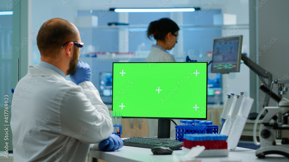 Researcher looking at chroma key display in modern equipped lab analysing virus evolution. Team of microbiologists doing vaccine research writing on device with green screen, isolated, mockup display. Researcher looking at chroma key display in modern equipped lab analysing virus evolution. Team of microbiologists doing vaccine research writing on device with green screen, isolated, mockup display.