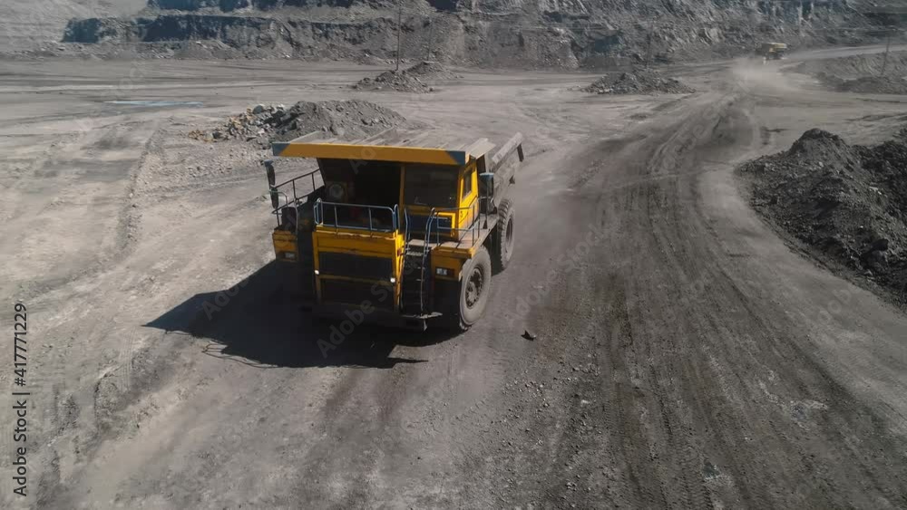 Large quarry dump truck. Loading rock in dumper. Loading coal into truck. Mining car machinery to transport coal. Open pit mine quarrying extractive industry stripping work. Big Yellow Mining Trucks Large quarry dump truck. Loading rock in dumper. Loading coal into truck. Mining car machinery to transport coal. Open pit mine quarrying extractive industry stripping work. Big Yellow Mining Trucks