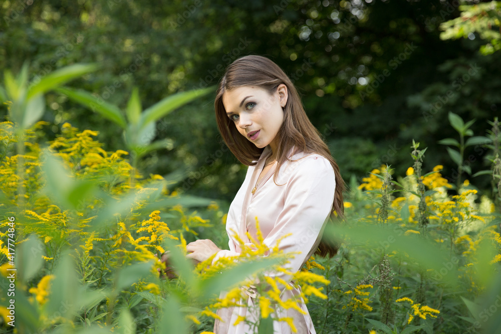 A beautiful woman in a light summer dress on a path and a forest meadow background. A beautiful woman in a light summer dress on a path and a forest meadow background.