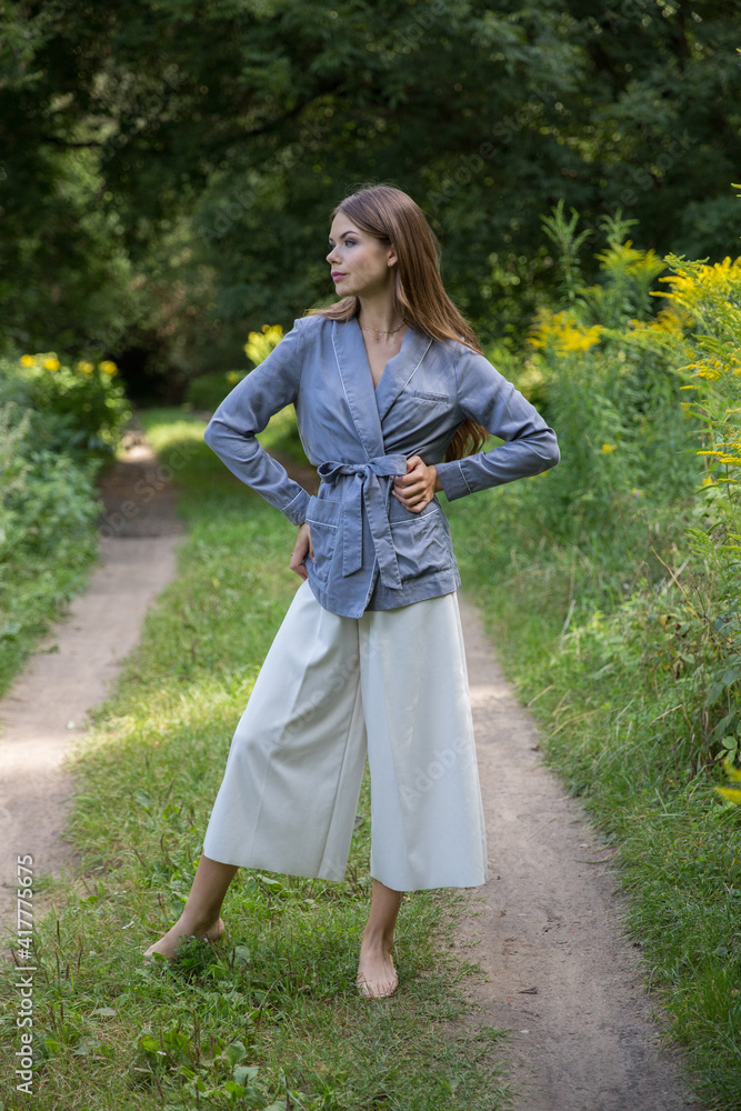 A beautiful brunette stands on a summer forest path. A beautiful brunette stands on a summer forest path.