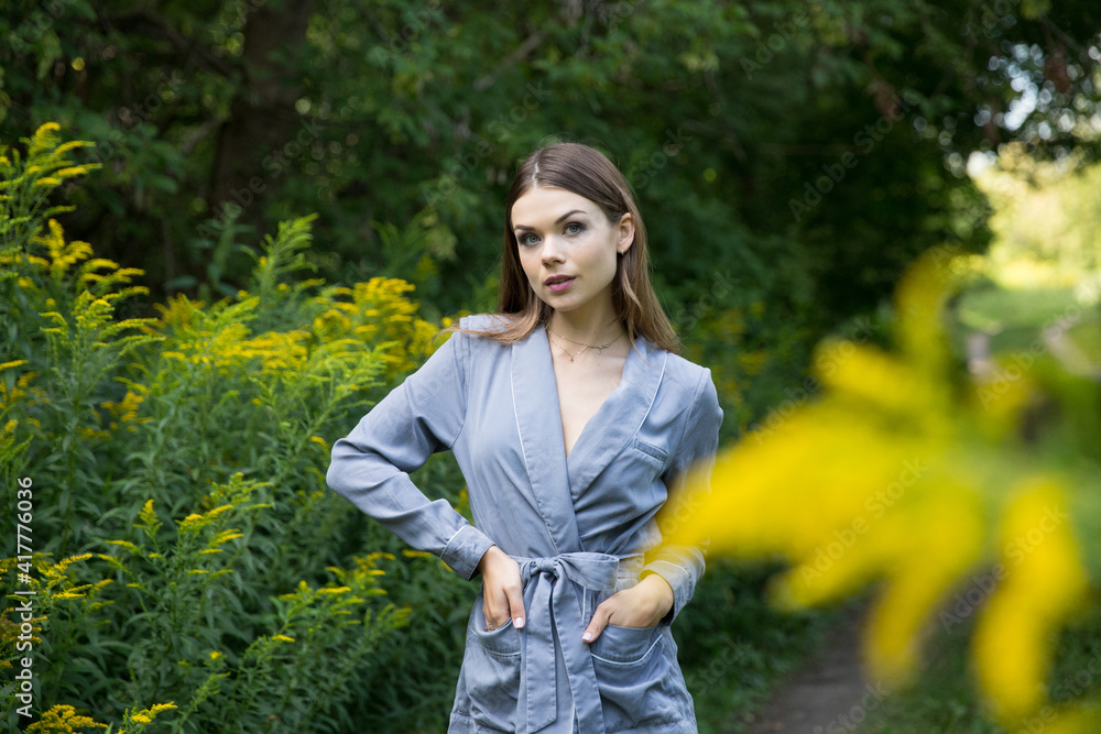 A beautiful brunette stands on a summer forest path. A beautiful brunette stands on a summer forest path.