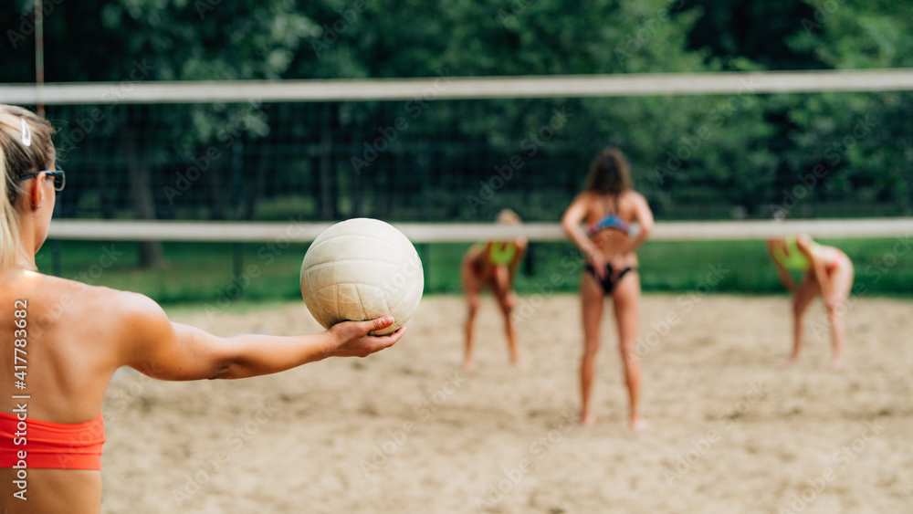 Fototapeta premium Beach Volleyball, Female Player Serving the Ball