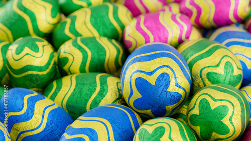 Multicolored, foil wrapped Easter Egg background. Beautiful Easter Wallpaper with, patterned Pink, Blue and Green Eggs. 3D Render 