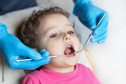 examination, treatment teeth children. medical checkup oral cavity with instruments. dental hands, child in office. Cute girl smiling stomatology. kid in dentist chair. concept health, medicine