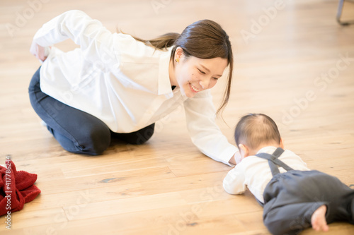 室内で、赤ちゃんと遊ぶお母さん