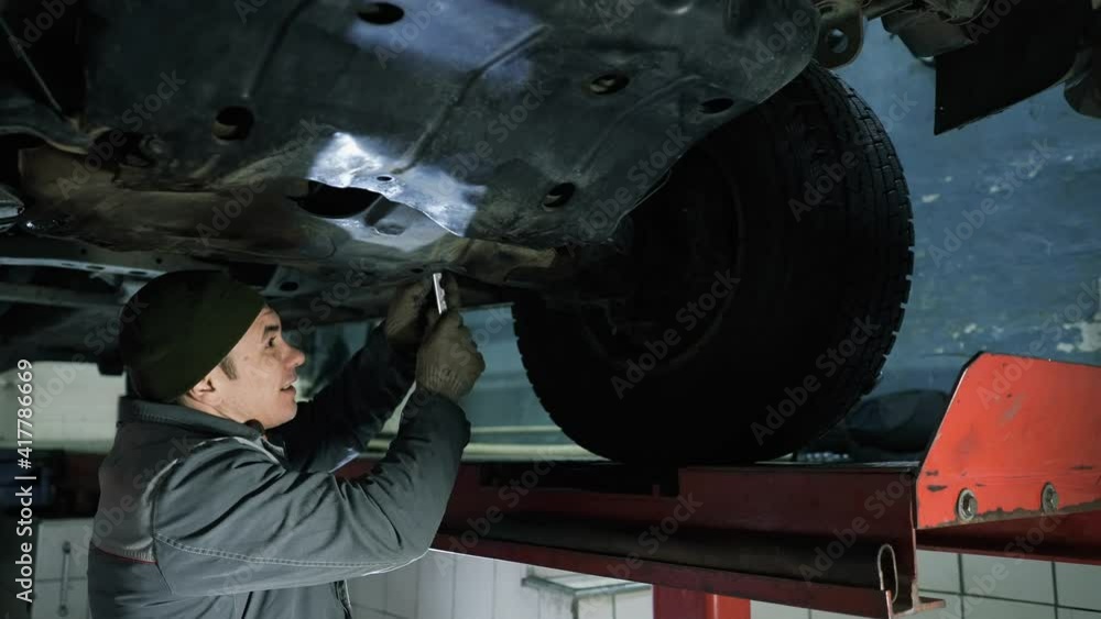 The mechanic fixes the undercarriage of the car. The mechanic fixes the undercarriage of the car.