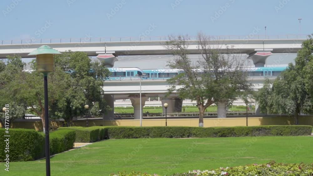 Dubai Metro RTA Trains On The Railway Spanning Across Al Rashidiya Park In Dubai, United Arab Emirates At Daytime. wide shot Dubai Metro RTA Trains On The Railway Spanning Across Al Rashidiya Park In Dubai, United Arab Emirates At Daytime. wide shot