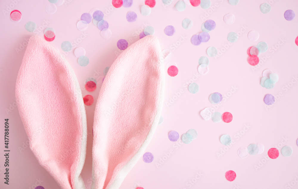 Easter greeting card  .Pink  bunny ears  on pink  pastel background  wint confetti with,  copy spase  . Easter minimal concept. Flat lay. advertising concept .