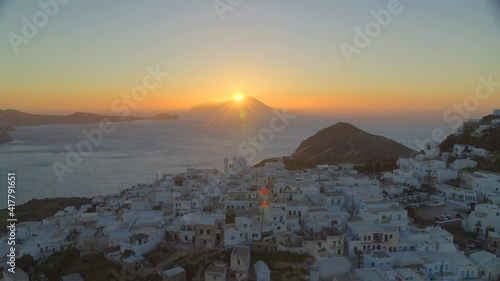 Aerial View of White Houses in Plaka Village and Sun Setting Behind Mountain photo