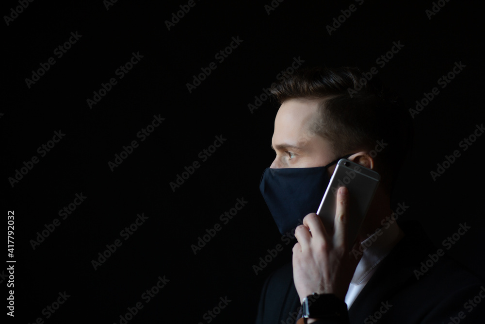 Close up of young businessman wearing a protective face mask while talking on a mobile phone. Copy space.