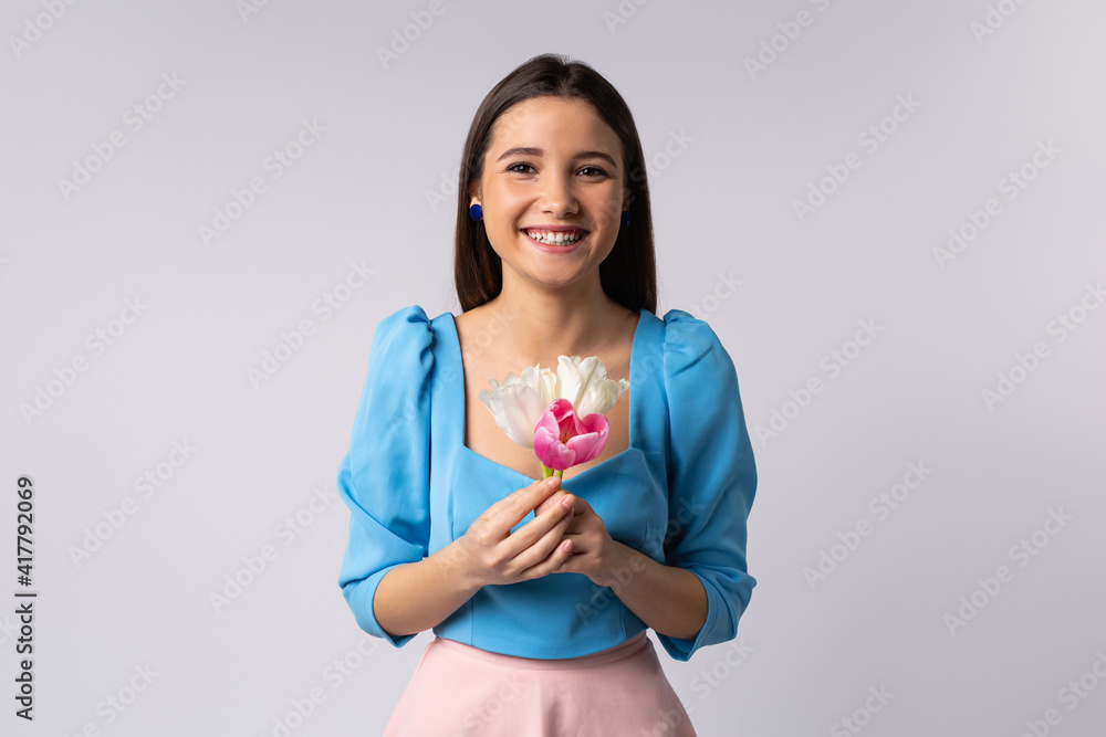 Happy girl posing with tulips. Spring Festival on a gray background with side space for your text or advertising. Springtime happiness Happy girl posing with tulips. Spring Festival on a gray background with side space for your text or advertising. Springtime happiness