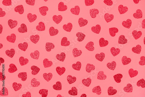 Bright festive red background with glitter hearts - St. Valentine's Day celebration concept. Love backdrop for greeting card, copy space for your text. Selective focus, toned image