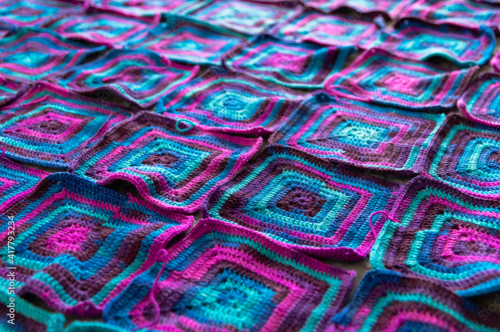 Fototapeta premium Crochet product from multicolored threads. Many squares crocheted. Handmade backdrop.