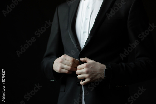 Cropped shot of groom in a jacket. The hands of man prepares in the morning for the wedding ceremony. 
