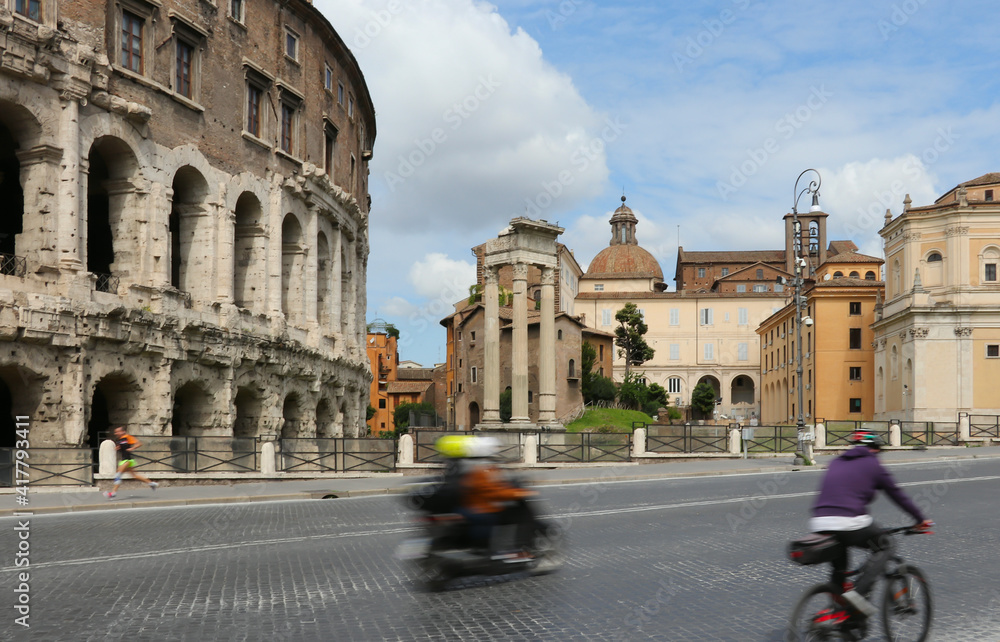 The effect of blurry traffic on the street of ancient Rome of various vehicles. Motorcyclist, cyclist and running man move at different speeds on the background of ancient buildings