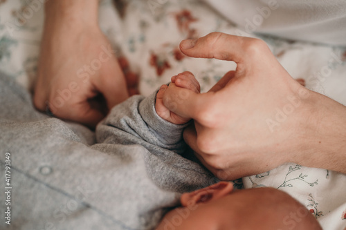 Newborn baby holds dad's hand. Close up of hands of child and parents