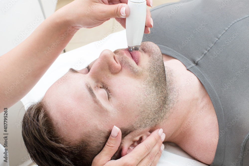 A man is made a cosmetic procedure mask to clean the healing skin of the face in a beauty salon. A man is made a cosmetic procedure mask to clean the healing skin of the face in a beauty salon.