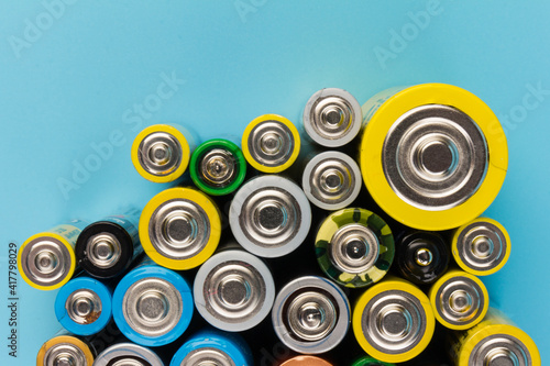 Photo of alkaline batteries on blue background. Recycling of rechargeable NiMH batteries. The different size of accumulators. Copy space.
