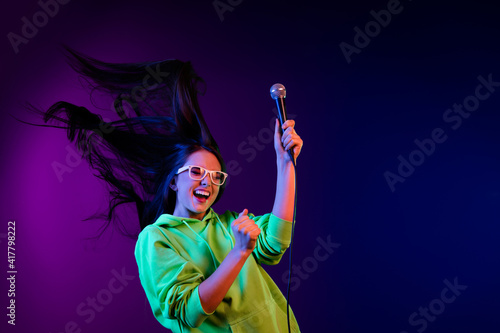 Photo of cheerful crazy funky young woman raise microphone fly hair isolated on colorful neon background