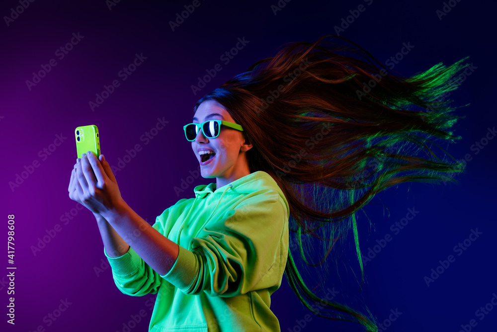 Photo of amazed shocked young woman look phone fast internet fly hair isolated on colorful neon background - obrazy, fototapety, plakaty 
