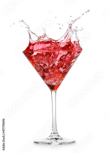 red cocktail splashing out of a martini cup isolated on white background
