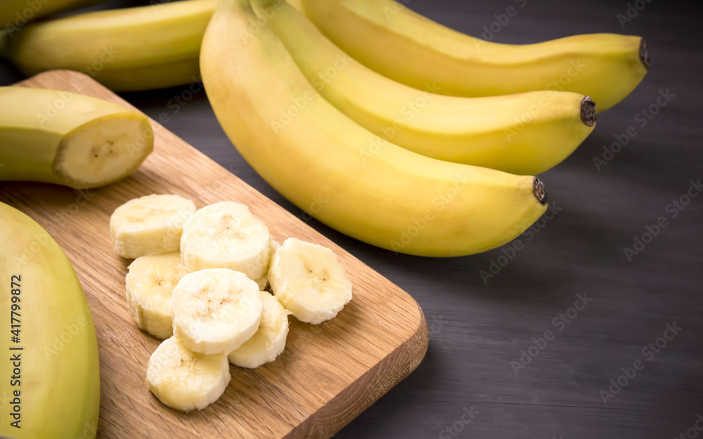 A bunch of bananas and a sliced banana on a table. A bunch of bananas and a sliced banana on a table.