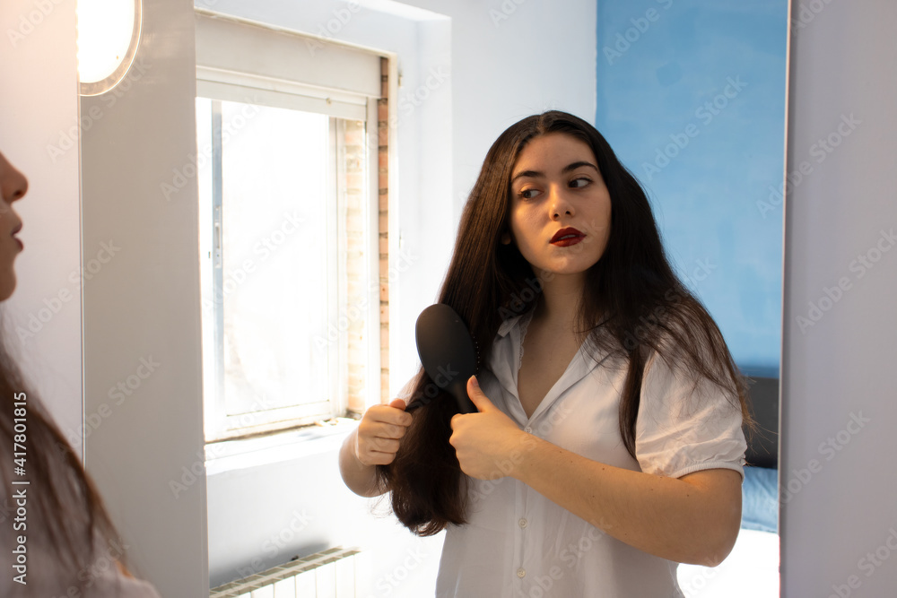 Woman combing her hair in front of the mirror. Woman combing her hair in front of the mirror.