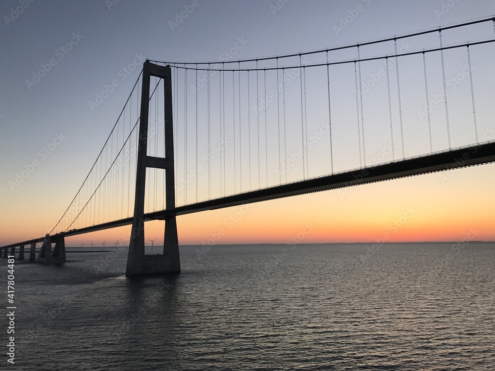 Brücke Hängebrücke Spannbeton Hohlkastenbrücke Storebæltsbroen Brückenzug in Dänemark in der Meerenge Großer Belt zwischen den Inseln Fünen und Seeland von einem Kreuzfahrtschiff bei Sonnenuntergang Brücke Hängebrücke Spannbeton Hohlkastenbrücke Storebæltsbroen Brückenzug in Dänemark in der Meerenge Großer Belt zwischen den Inseln Fünen und Seeland von einem Kreuzfahrtschiff bei Sonnenuntergang