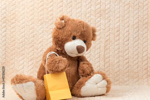 A teddy bear with a gift bag sits on the sofa